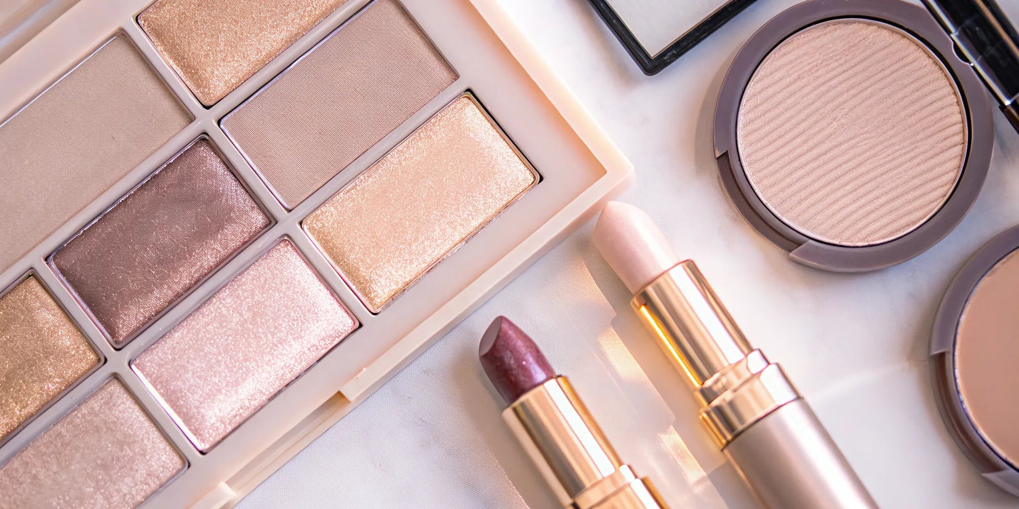Luxury monochromatic makeup palette flat lay with coordinating neutral lipstick, eyeshadow, and blush