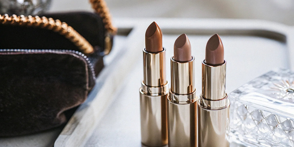 Three different shades of satin finish nude lipsticks in luxe gold tubes.