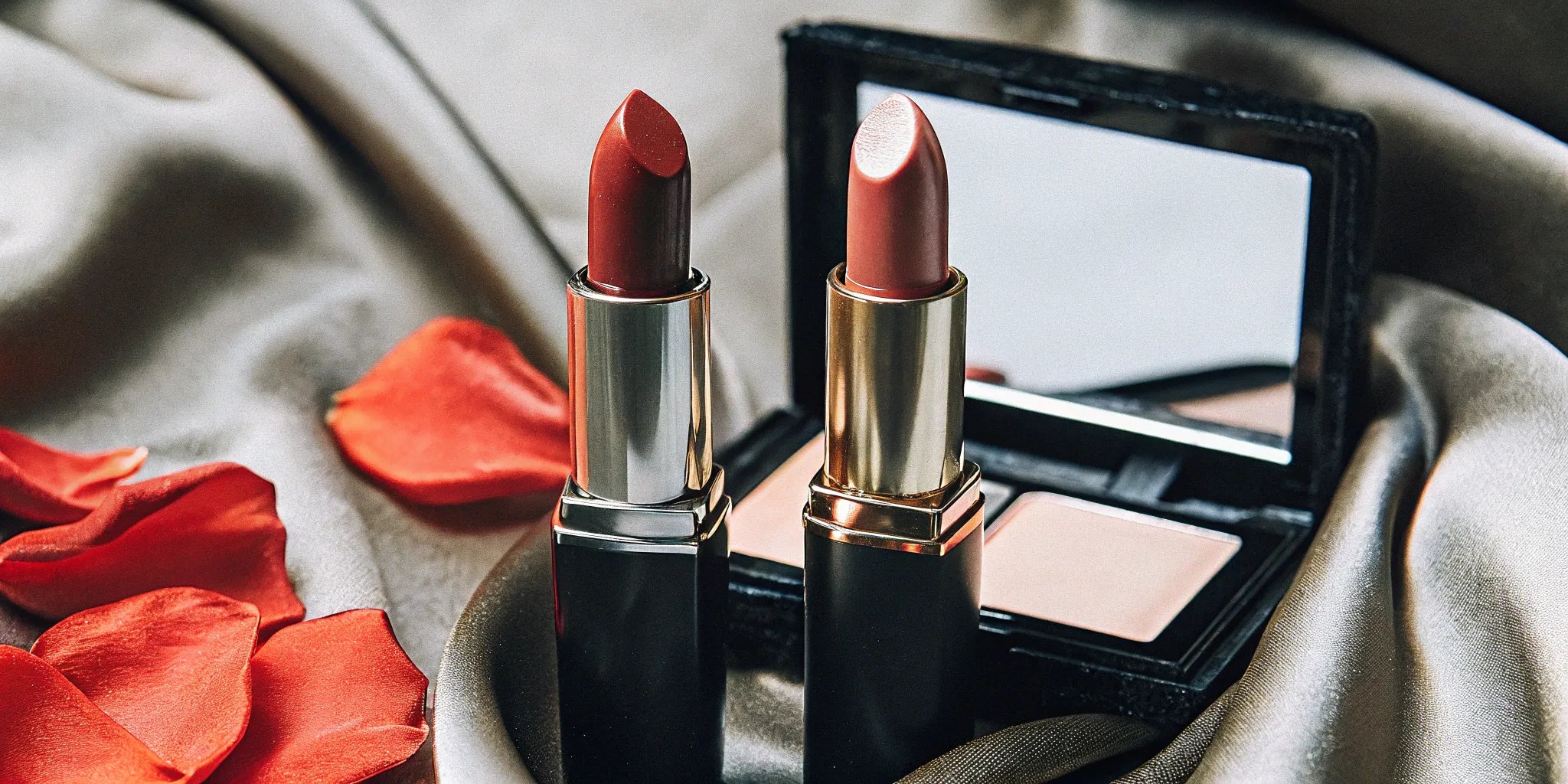 Creamy vs matte lipstick tubes on silk fabric, comparing their different textures and finishes.